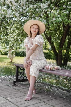 An attractive long-haired woman walks in the spring in the park of blooming apple trees. Spring portrait of a woman