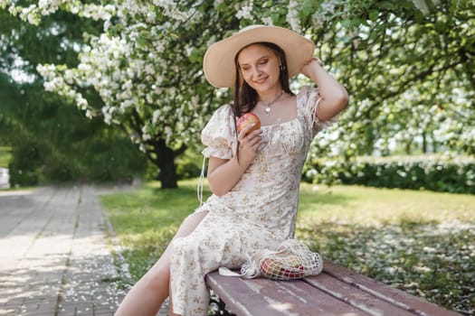 An attractive long-haired woman walks in the spring in the park of blooming apple trees. Spring portrait of a woman