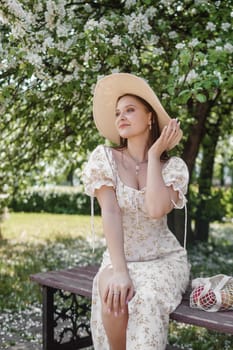 An attractive long-haired woman walks in the spring in the park of blooming apple trees. Spring portrait of a woman