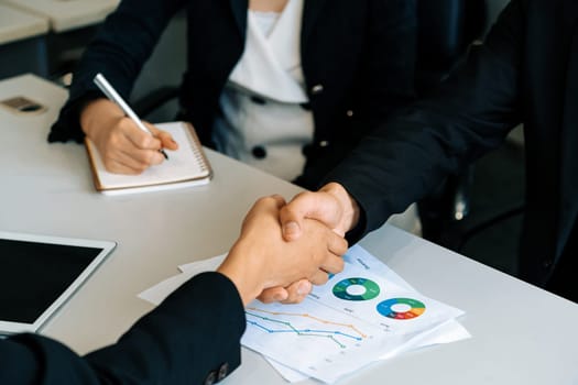 Business people agreement concept. Businessman and Asian businesswoman do handshake in the office. uds