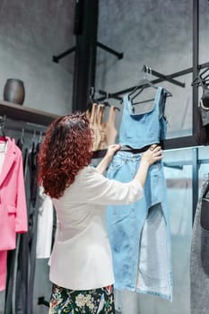 Shopping woman, women's fashion clothes in a store, boutique. Woman choosing clothes in a store.