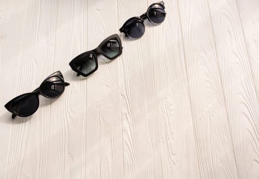Stylish black sunglasses. Summer background mockup template text. pattern top view above white wooden background. Summer fashion accessories for beach. Women summer design sunglasses. Vacation concept