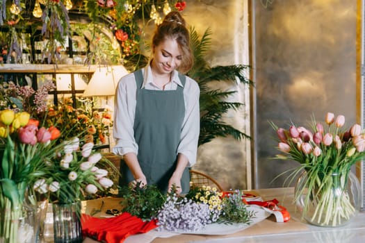 A woman in her florist shop collects bouquets of flowers. The concept of a small business. Bouquets of tulips for the holiday on March 8