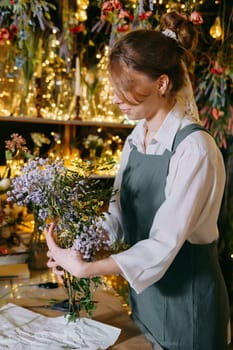 A woman in her florist shop collects bouquets of flowers. The concept of a small business. Bouquets of tulips for the holiday on March 8