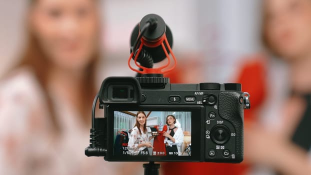 Rear view behide camera screen display two women influencer shoot vlog video review clothes prim social media or blog. Girls with apparel studio lighting for live streaming marketing recording session