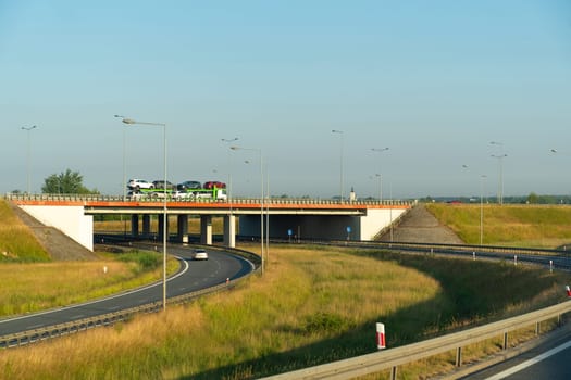 Vehicles cross an overpass in the early morning light, with clear skies and open roads.