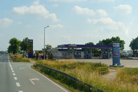 Kutno, Poland - June 16, 2023: A sunny day captures a rural gas station MOYA by the roadside, with clear blue skies and a few patrons in the parking area.