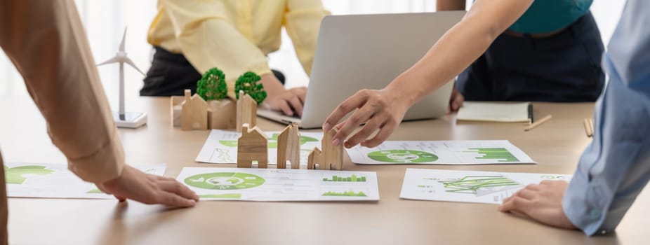 Wooden block represented green city and wind mill represented renewable energy was placed at center of green business meeting table with environmental document. Green business concept. Delineation.