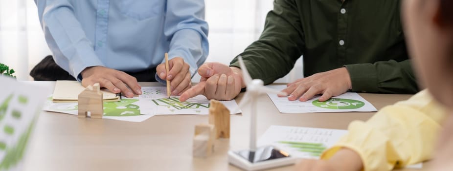 Green business meeting represented renewable energy. Skilled businesspeople discuss green business investment at table with environmental documents. Closeup. Focus on hand. Delineation.