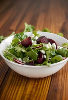 spring salad with boiled beets, lettuce leaves and herbs in a bowl on a wooden table. AI generated image.