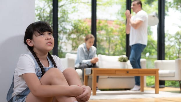 Stressed and unhappy young girl huddle in corner crying and sad while her parent arguing in background. Domestic violence at home and traumatic childhood develop to depression. Panorama Synchronos