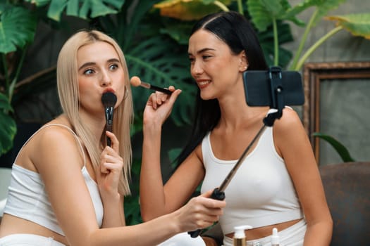 Two beautiful content creator making natural beauty and cosmetic tutorial on green plant garden video. Beauty blogger showing how to beauty care to social medial audience using selfie stick . Blithe
