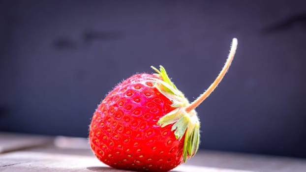 Close up of one strawberry on wooden board isolated on black background