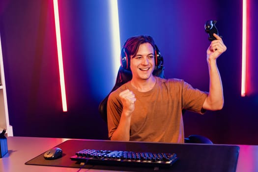 Enjoy smart gaming streamer with control joystick, playing game online of live streaming social media group with team skilled players on computer at modern technology cyber neon light room. Pecuniary.