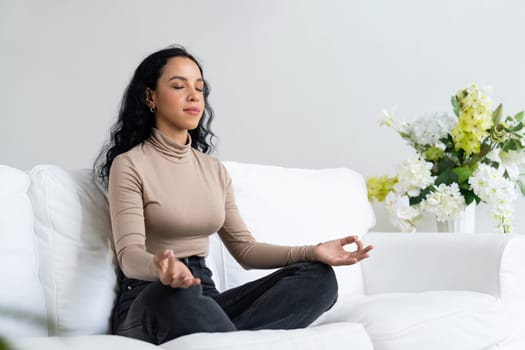 Young African American woman practice crucial mindful meditation at home living room for improving mental health strength and peaceful beautiful living