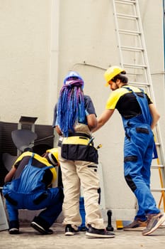 Diverse team of competent mechanics working outside, checking for jammed air filters hindering hvac system airflow, causing heating system to work harder and consume more energy