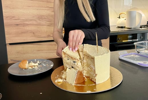 Female hands cut off a piece of festive cake with a knife. High quality photo