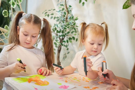 Cute little sisters are painting on table. Preschooler, 4 and 8 years child in living room. Small girl kids doing homework, home schooling concept