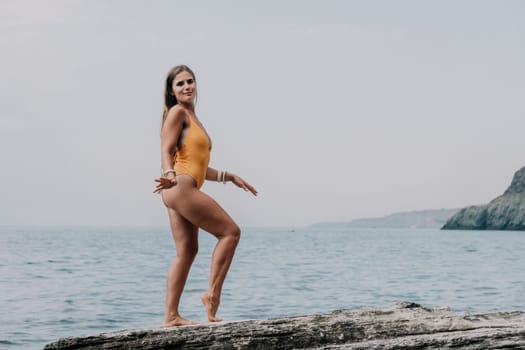 Woman meditating in yoga pose silhouette at the ocean, beach and rock mountains. Motivation and inspirational fit and exercising. Healthy lifestyle outdoors in nature, fitness concept.