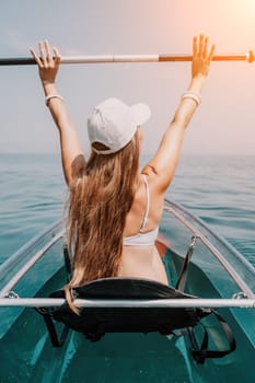 Woman in kayak back view. Happy young woman with long hair floating in transparent kayak on the crystal clear sea. Summer holiday vacation and cheerful female people having fun on the boat.