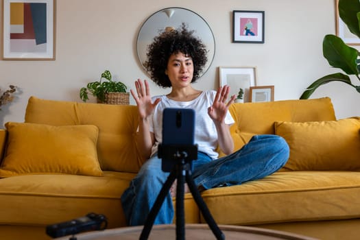 Young african american mixed race woman recording video talking to followers during live stream on social media. Female content creator using phone to communicate with subscribers. Technology concept.