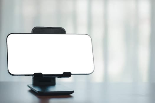 Office workspace with blank white screen smartphone on a table, Surrounded by business and technology elements