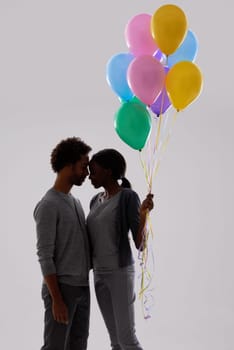 Couple, silhouette and love with party balloons for celebration, event or romance on a gray studio background. Man and woman with colorful blowups of helium for date or anniversary on mockup space.
