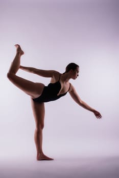 Young beautiful female yoga posing on gray studio background