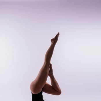 Young beautiful female yoga posing on gray studio background