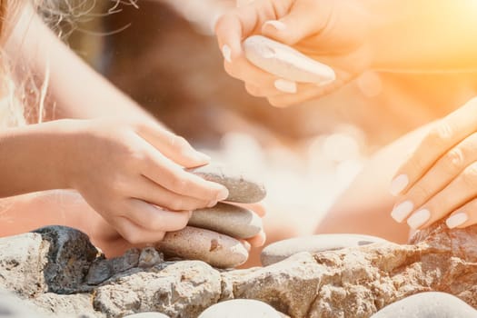 Balanced Pebbles Pyramid on the Beach on Sunny Day and Clear Sky at Sunset. Blue Sea on Background Selective focus, zen stones on sea beach, meditation, spa, harmony, calm, balance concept.