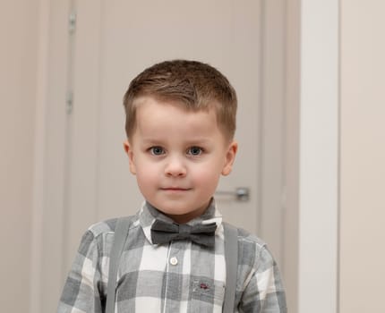 Emotions of calm, thoughtfulness on the child s face. A small handsome boy of 4 years old in a shirt with a bow tie shows a mime with a facial expression. Close-up. portrait