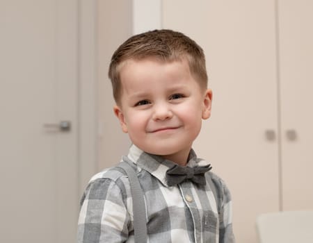 Emotions of happiness, fun, joy and delight on the child s face. A small handsome boy of 4 years old in a shirt with a bow tie shows a mime with a facial expression. Close-up. portrait
