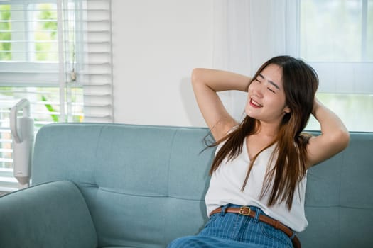 Asian young woman enjoying free time relaxing put arm hand back behind head on sofa in living room at home, Happy female feeling relax comfort after homework