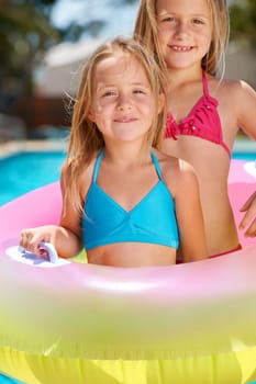 Happy, portrait and kids with inflatables in swimming pool for adventure at resort on vacation. Holiday, games or friends relax together with toys for fun in water, summer or children with fashion.