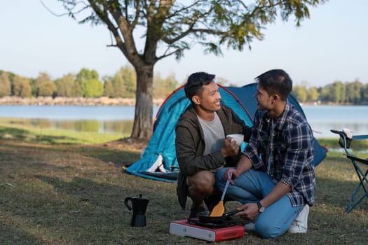 Asian LGBTQ couple drinking coffee in a romantic camping tent. LGBTQ couple drinking coffee in a camping tent, enjoying nature, forest, camping atmosphere, LGBTQ, gay, gay men..