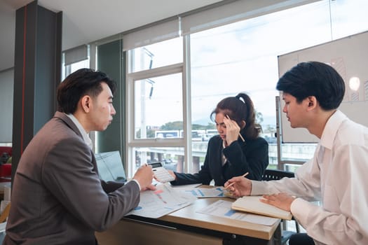 The Asian business team brainstormed and discussed work planning. Financial or statistical figures of the company in the conference room.