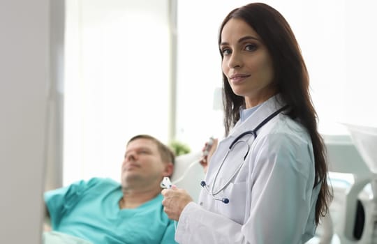 Female doctor sets dropper to patient in clinic. Treatment and examination organized as day hospital. Development measures for prevention diseases and maintaining healthy. Man is hospital