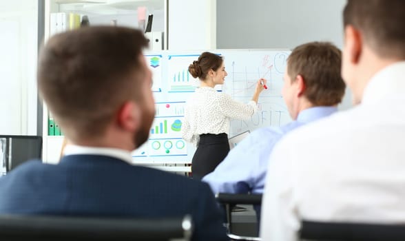 Smiling beautiful woman in office telling something important while showing information on white board