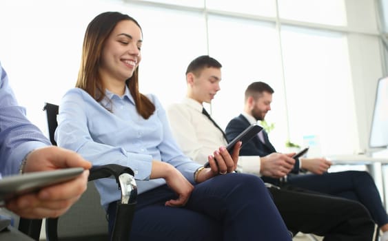 Bunch of people holding in hands electronic gadgets while sitting in line closeup