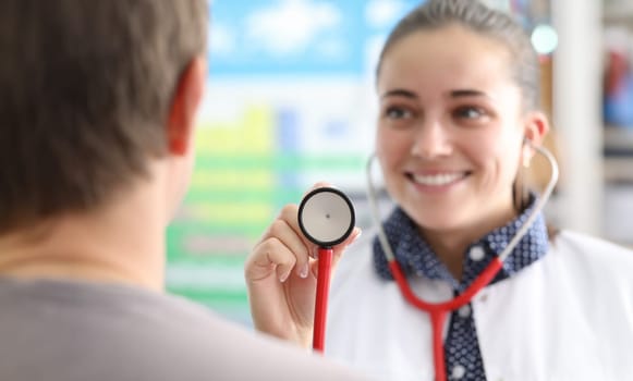 Female doctor shows patient stethoscope membrane. Bad habits and seasonal diseases. Patient is referred to hospital. Therapist's appointment provides comprehensive definition well-being