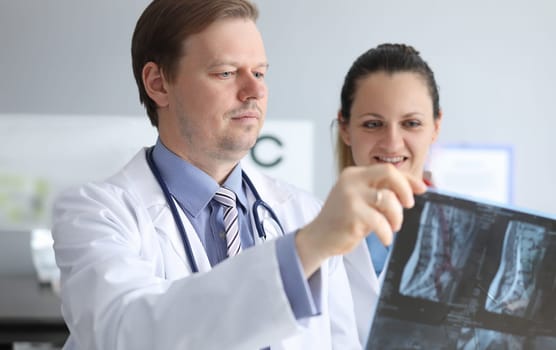 Male and female doctors carefully look at an x-ray. Magnetic laser therapy. Make an appointment with clinic. Success operation depends on knowledge and experience surgeon. Get surgeon consultation