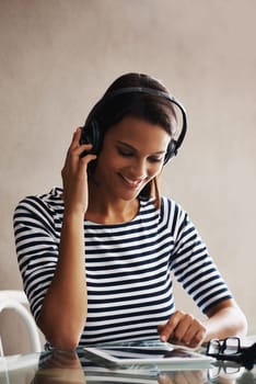 Woman, home and office with tablet, headphones and listening to podcast while working on touchscreen for freelance job. Female person, internet or online with headset for communication or consulting