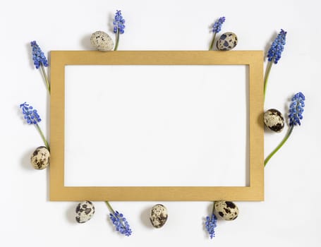 Easter quail eggs, fresh springtime flowers and golden frame.Top view, flat lay. Easter concept. Template for easter congratulation