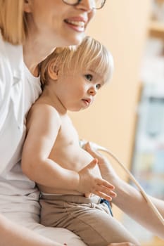 Small child being checked for heart murmur by heart ultrasound exam by cardiologist as part of regular medical checkout at pediatrician