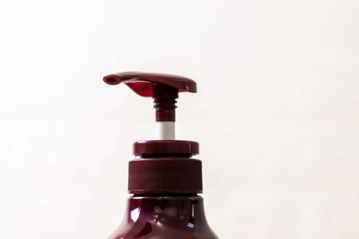 Part one bottle of burgundy eggplant color natural shampoo with dispenser on white background, side view close up. The concept of personal hygiene, cosmetics, beauty.
