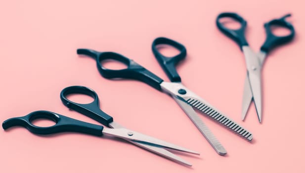 Set of three pairs of hairdresser's scissors on a pink background,close-up side view with depth of field. The concept of hairdressing, beauty salon, tools.