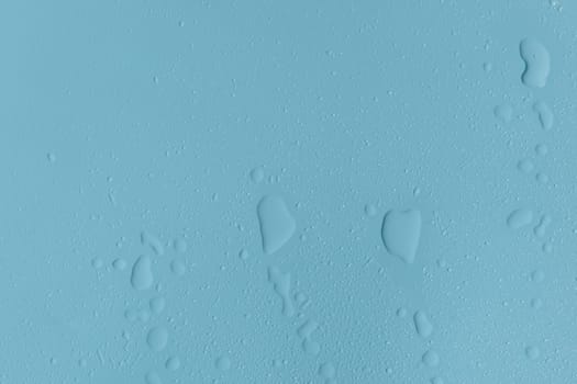 Beautiful blue background with splashes, large and small drops of water, flat lay closeup. Texture concept, backgrounds, wallpapers.