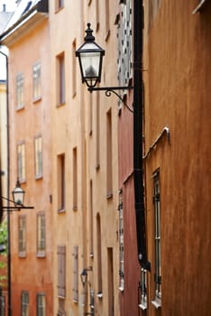 Travel, architecture and lamp in vintage alley of old town with history, culture or holiday destination in Sweden. Vacation, buildings and antique lantern in Stockholm with retro light ancient city.
