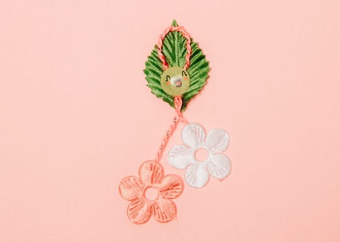 One beautiful homemade martisor made from flowers, a petal and a cheerful smiley face lies in the center on a pink background, flat lay close-up.