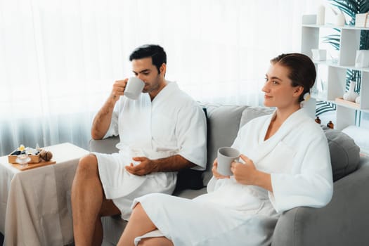 Beauty or body treatment spa salon vacation lifestyle concept with couple wearing bathrobe relaxing with drinks in luxurious hotel spa or resort room. Vacation and leisure relaxation. Quiescent